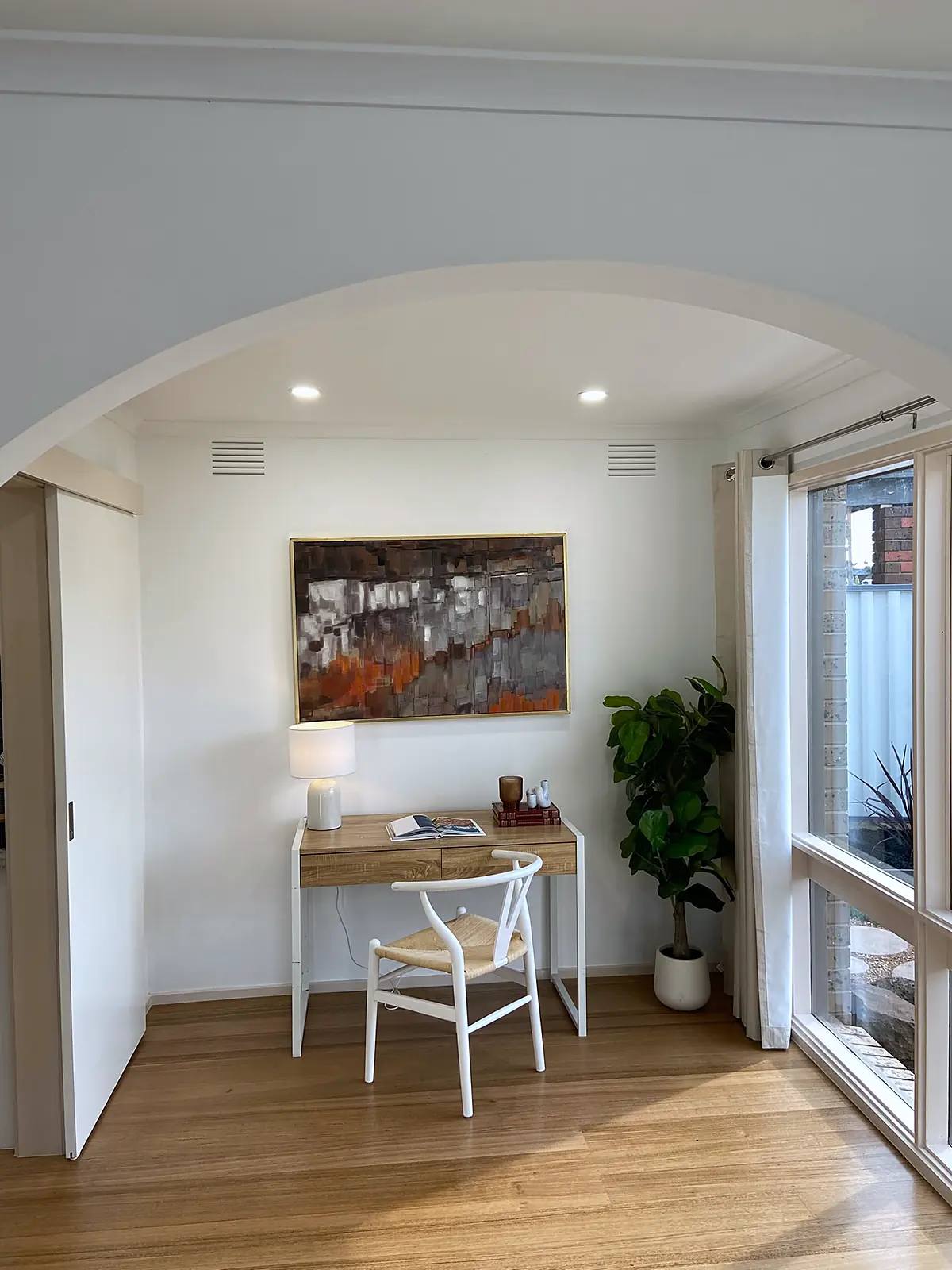 Study nook with desk and chair framed by an arch in a staged Kings Park home
