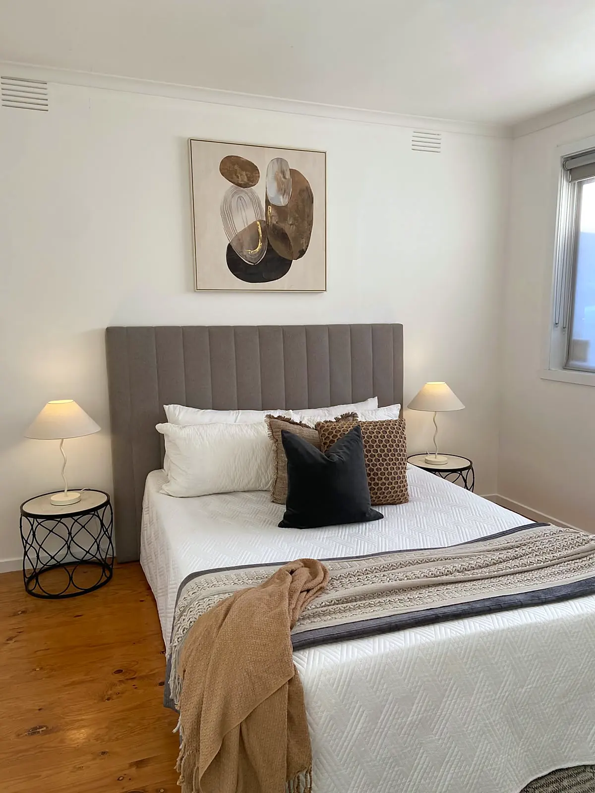 Bedroom staged with grey bedhead and abstract artwork on timber floors in a Lalor unit
