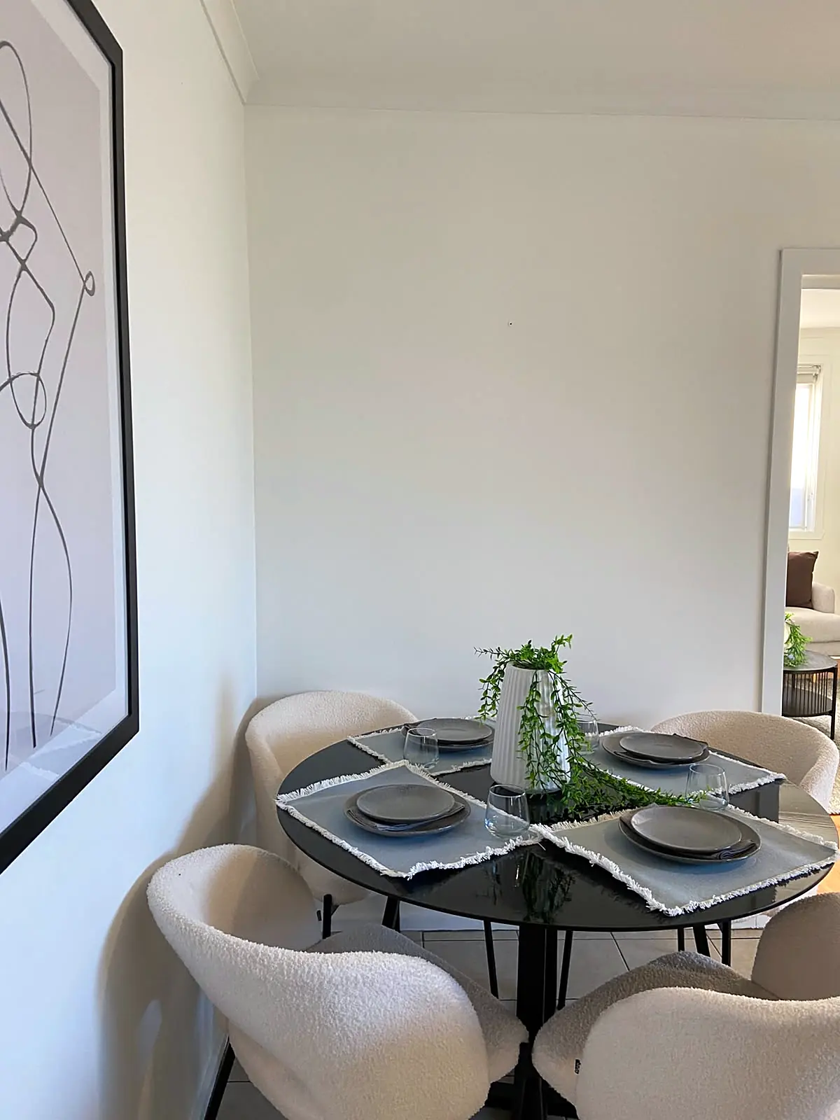 Round black dining table with boucle chairs in a staged Lalor unit