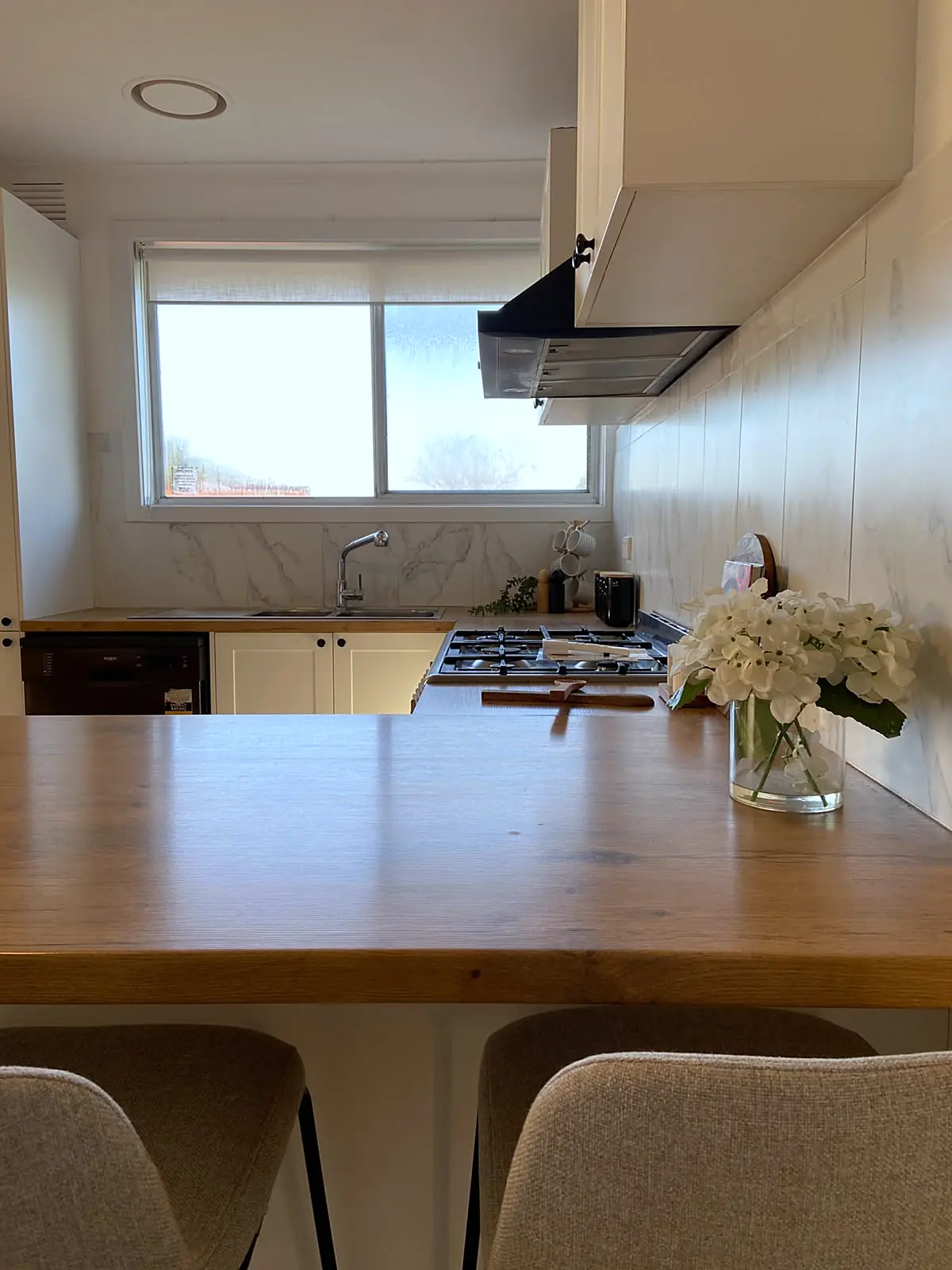Kitchen with timber benchtop styled with flowers in a Lalor unit
