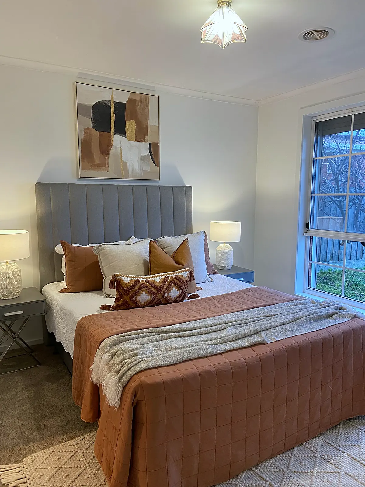 Main bedroom staged with grey bedhead and terracotta quilt in a Meadow Heights home
