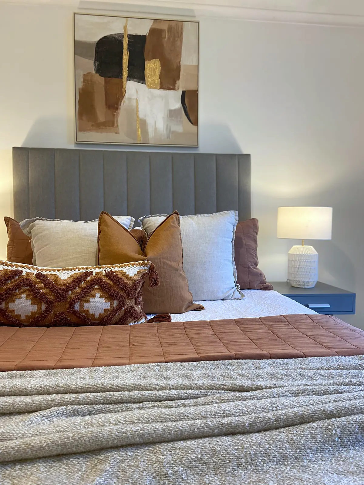 Bedroom styled with rust patterned cushions and abstract artwork in a Meadow Heights home