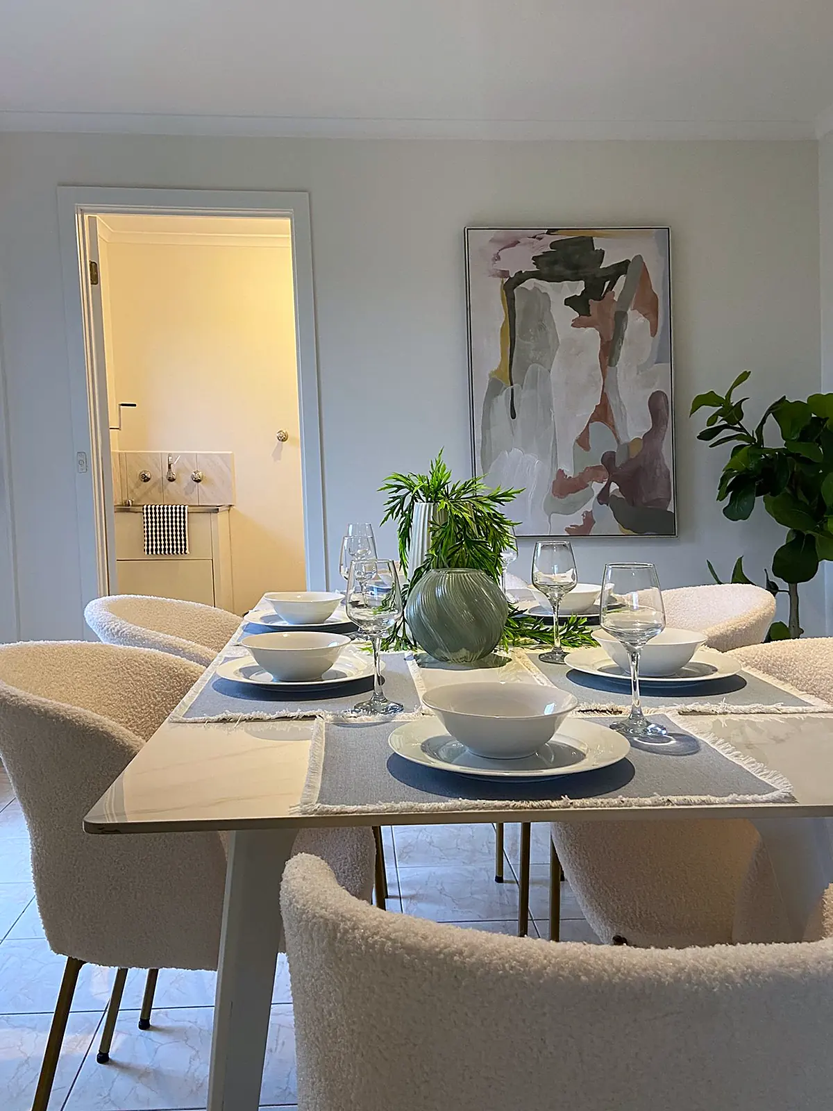 Dining table with boucle chairs and artwork in a staged Meadow Heights home