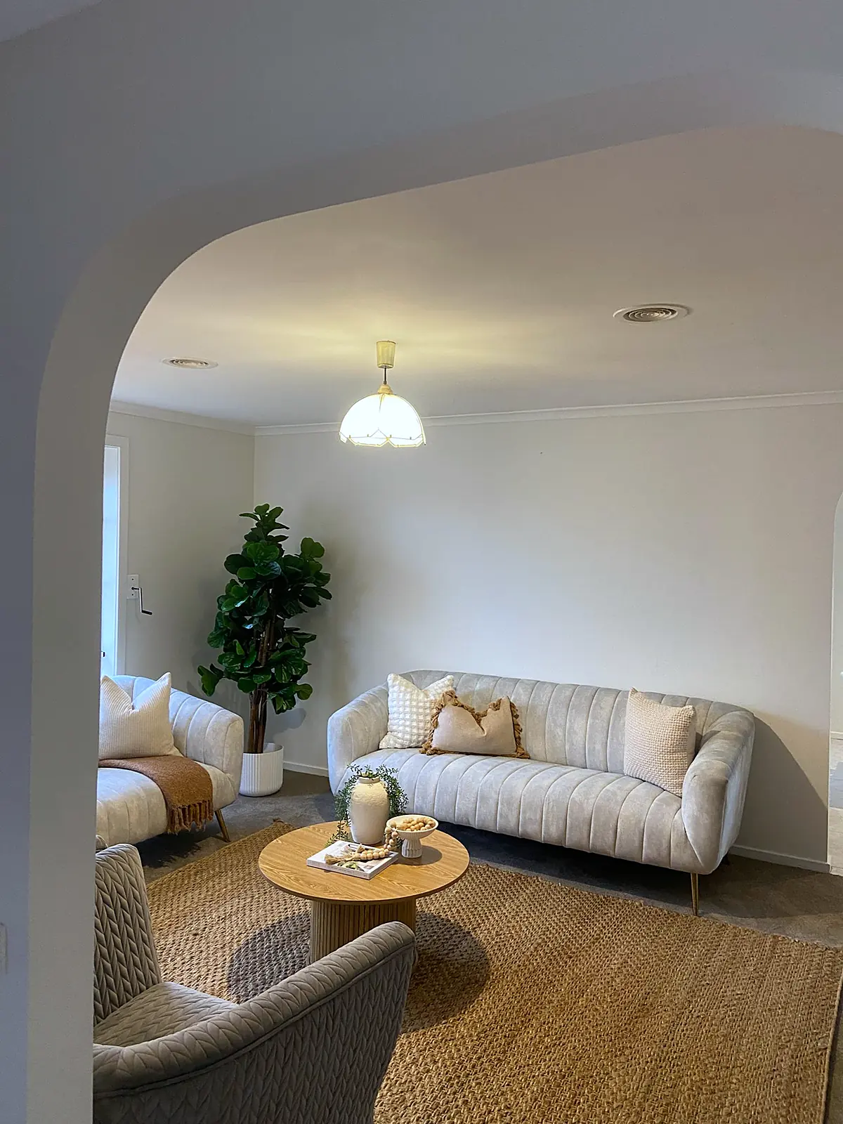 Lounge staged with curved sofa and jute rug seen through an archway in a Meadow Heights home