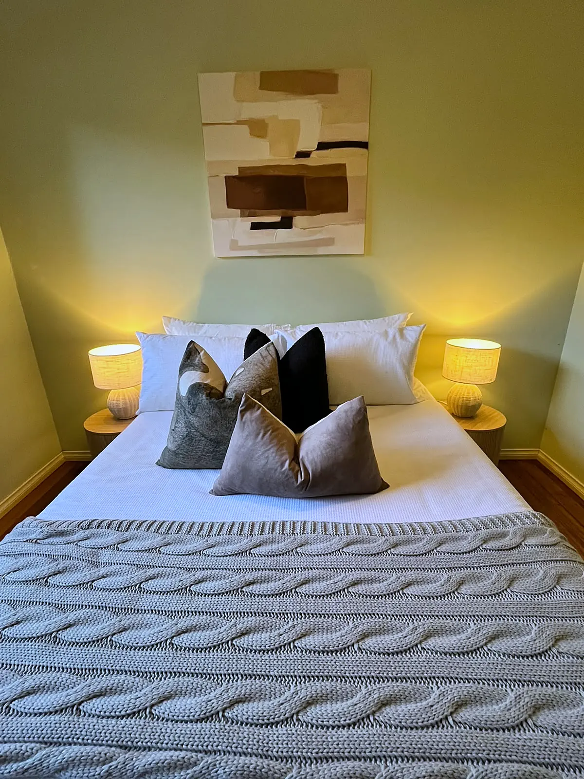Bedroom staged with grey cushions and knitted throw in a Melton home