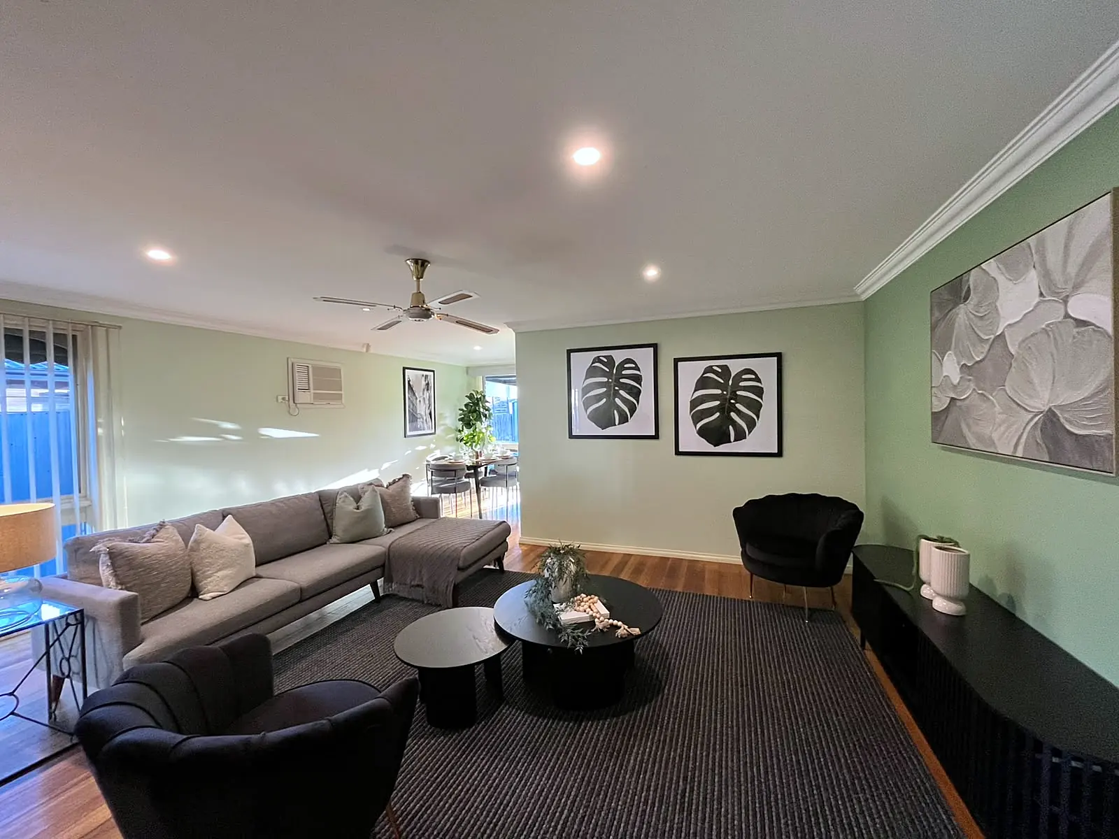 Family room with sage walls staged with grey sofas and dark rug in a Melton home