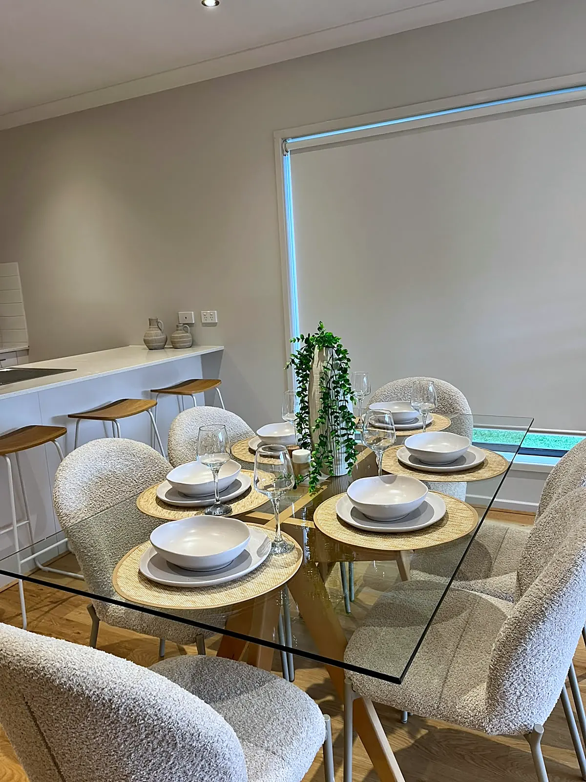 Dining area staged with glass table and boucle chairs in a Mernda home