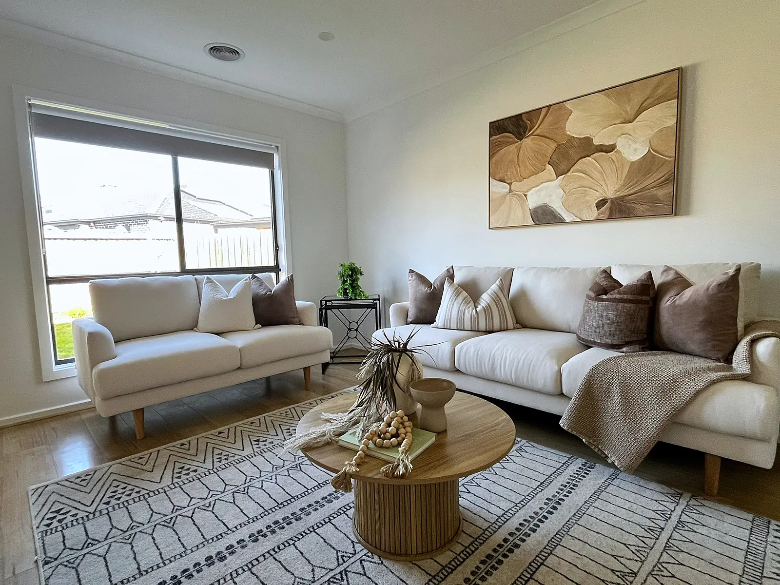Living room staged with cream sofas and round timber coffee table in a Mickleham home