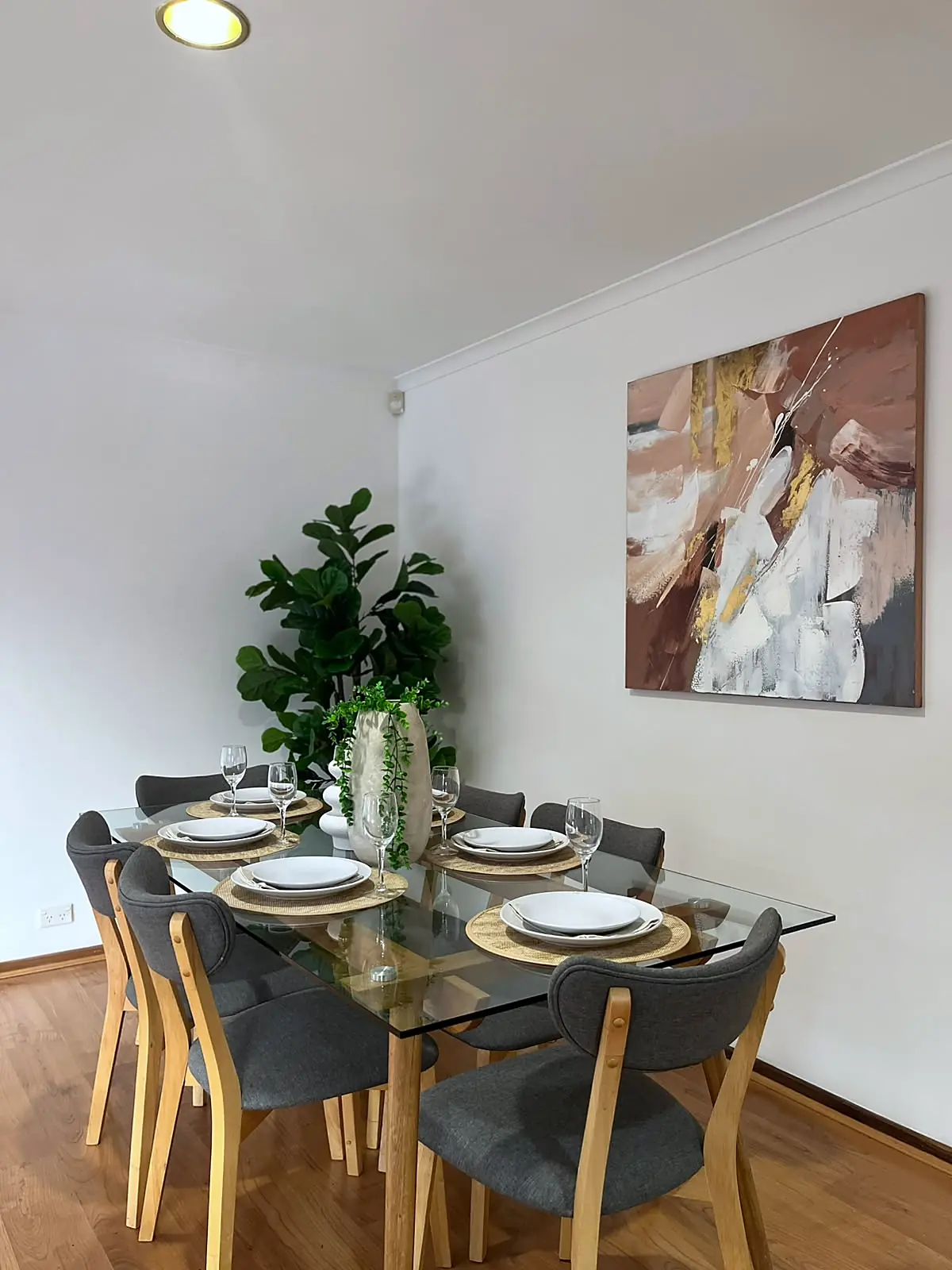 Glass dining table with six grey chairs and abstract artwork in a staged Mill Park home