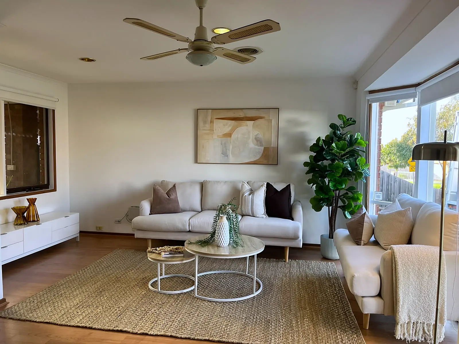 Living room staged with cream sofas and jute rug beside a bay window in a Mill Park home