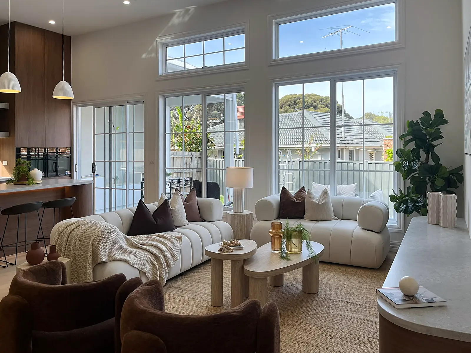 Living room staged with curved cream sofas beside tall windows in an Oak Park home