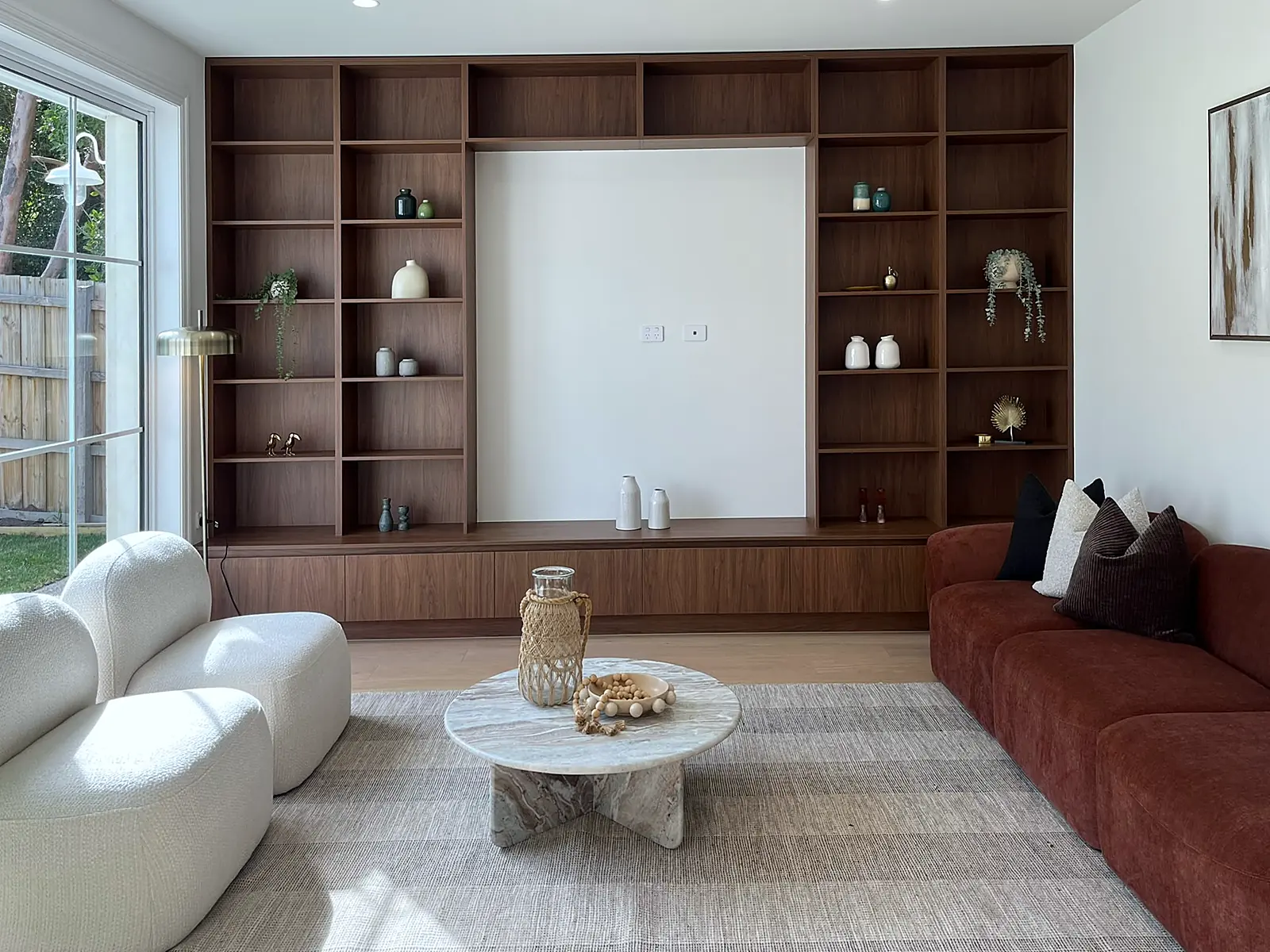 Second living room with built-in walnut shelving and rust sofa staged in an Oak Park home