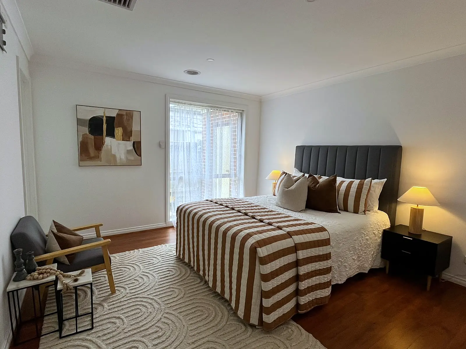 Main bedroom staged with striped throw and armchair in a Point Cook home