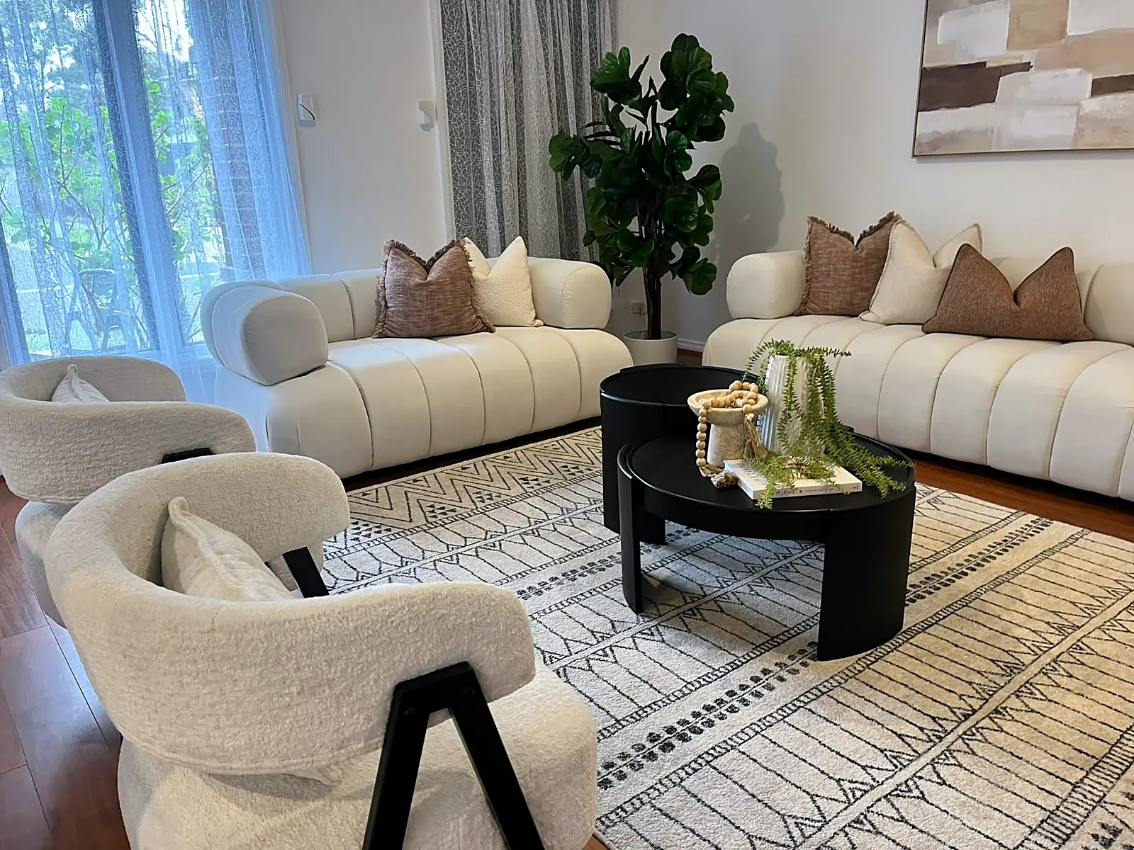 Curved boucle sofas and black coffee tables in a staged Point Cook lounge