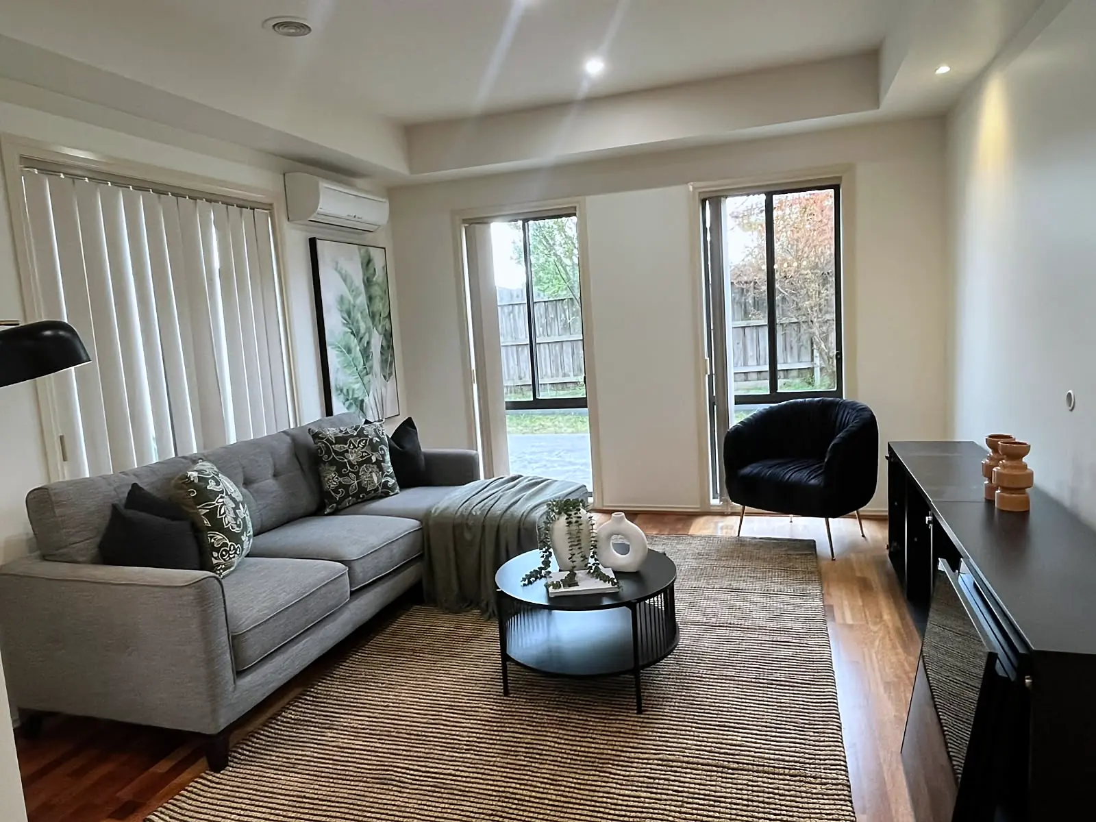 Staged living room with grey sofa and timber floors in a Roxburgh Park home
