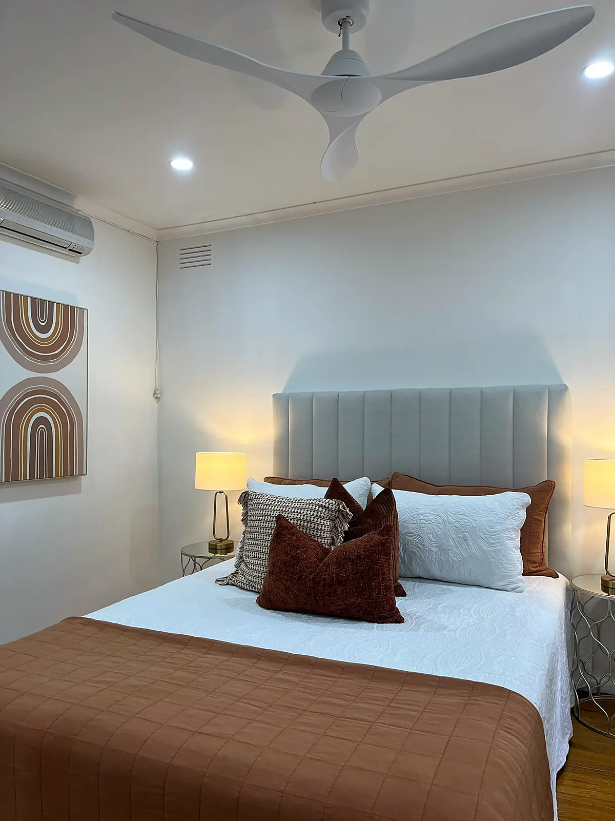 Bedroom staged with upholstered bedhead and rust quilt in a Seaholme home
