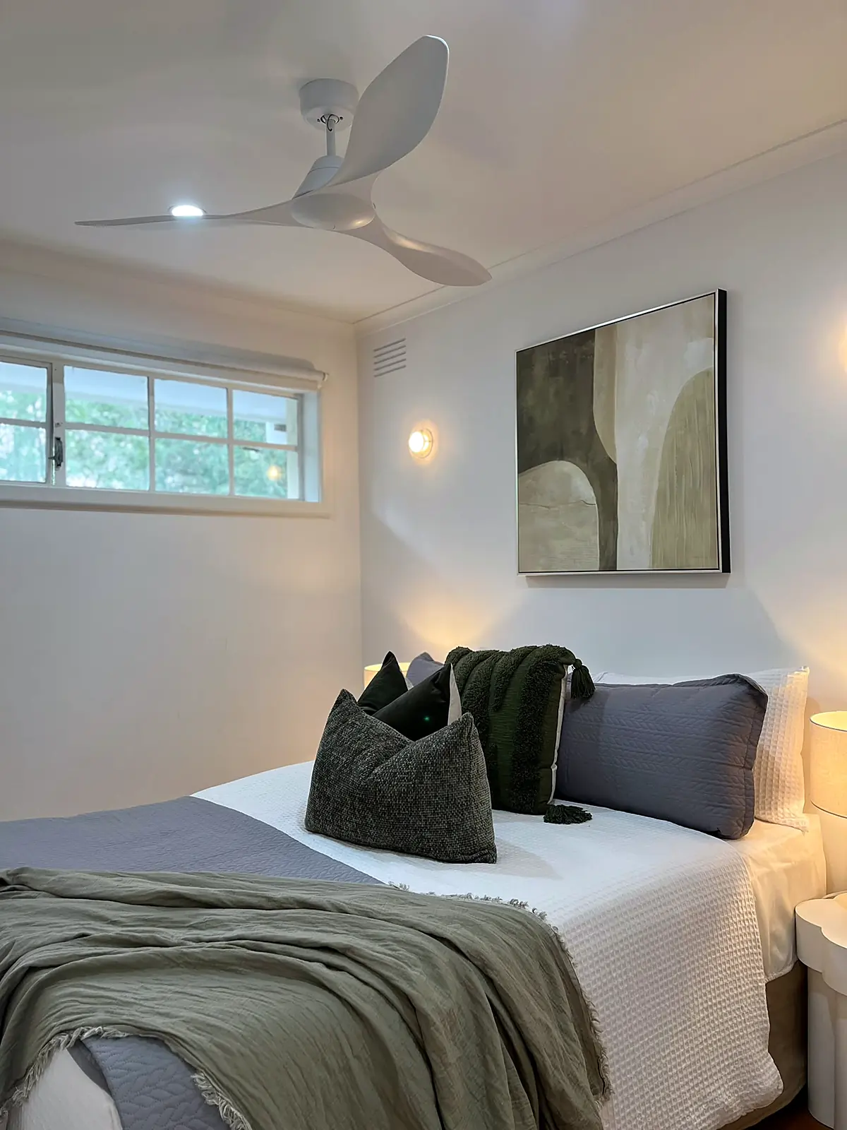 Bedroom styled with olive throw and abstract artwork in a Seaholme home