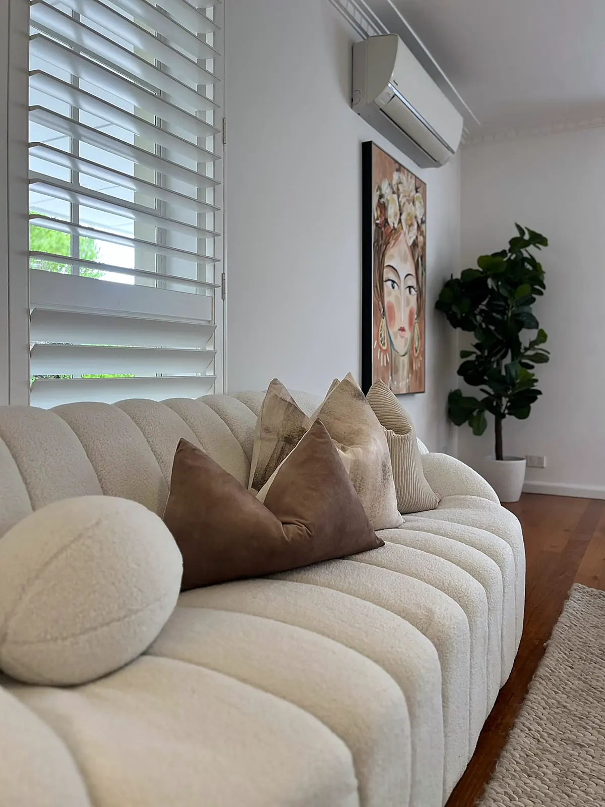 Curved boucle sofa beside plantation shutters in a staged Seaholme lounge