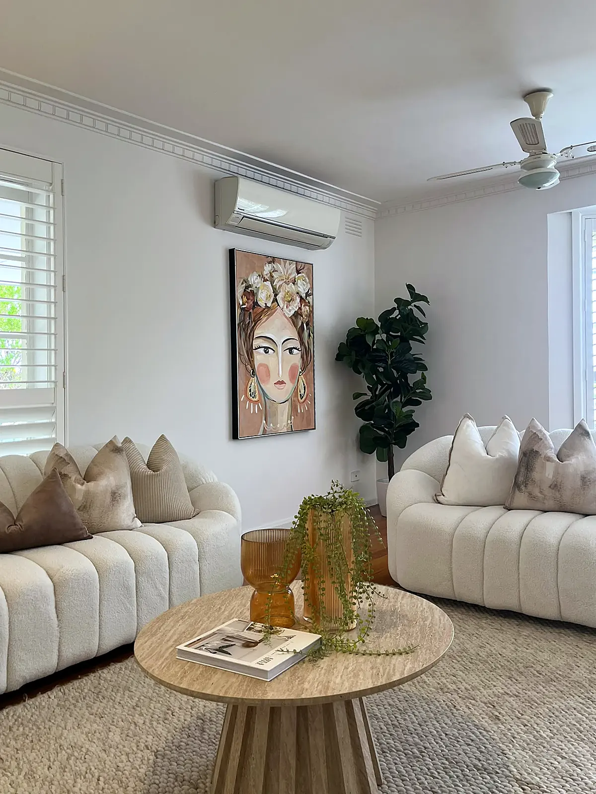 Lounge staged with two curved boucle sofas and round timber coffee table in a Seaholme home