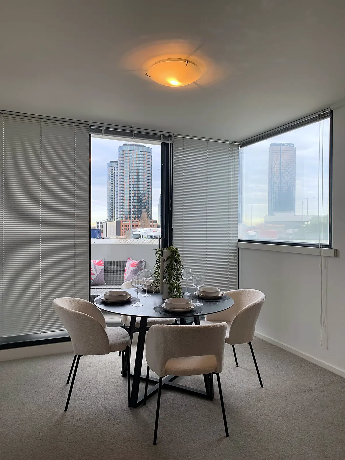 Round dining table for four beside corner windows in a staged Southbank apartment