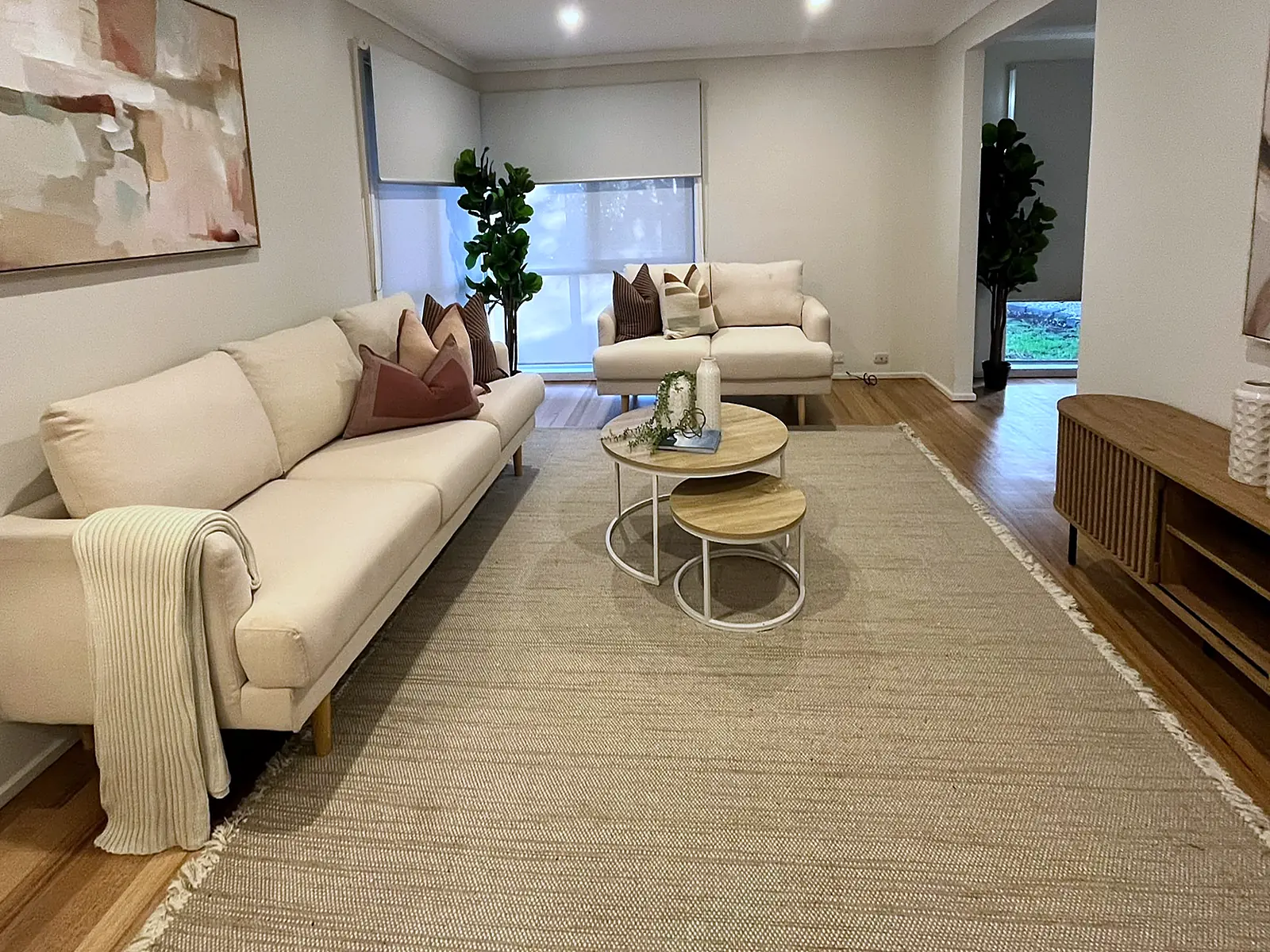 Open living room staged with cream sofa and large rug in a St Albans home