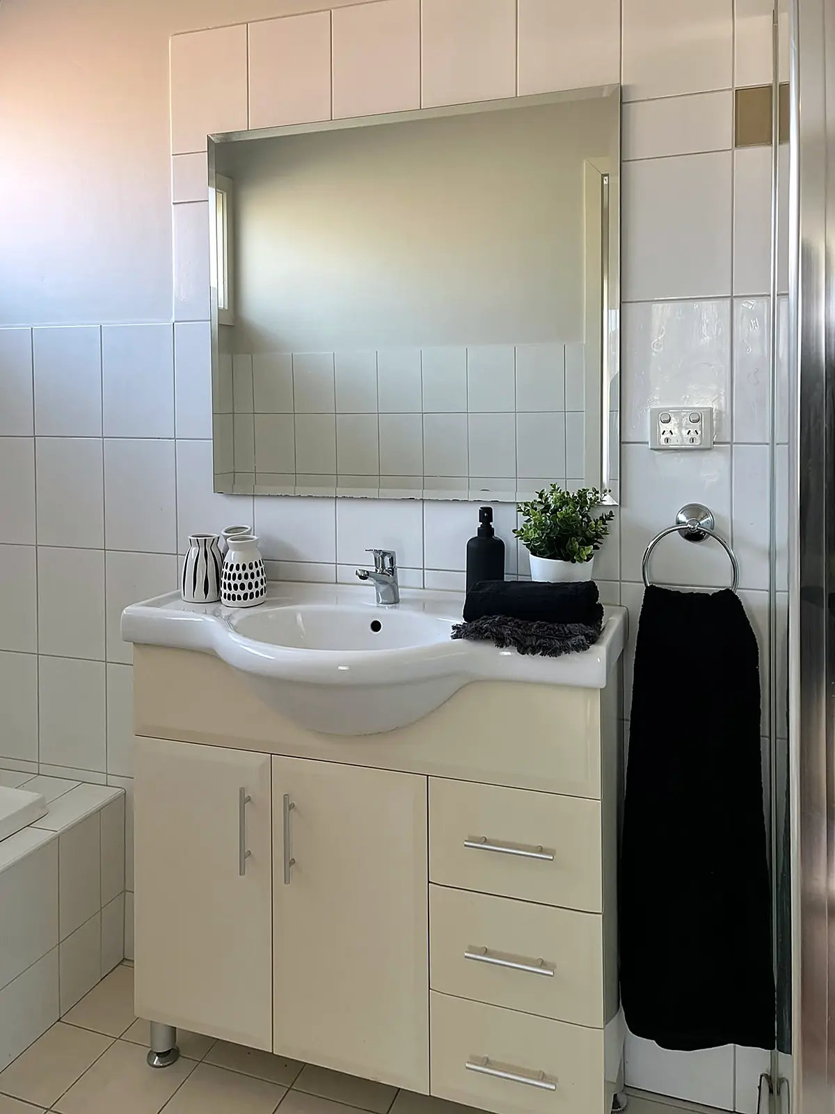 Bathroom vanity styled with towel and greenery in a Sunshine home