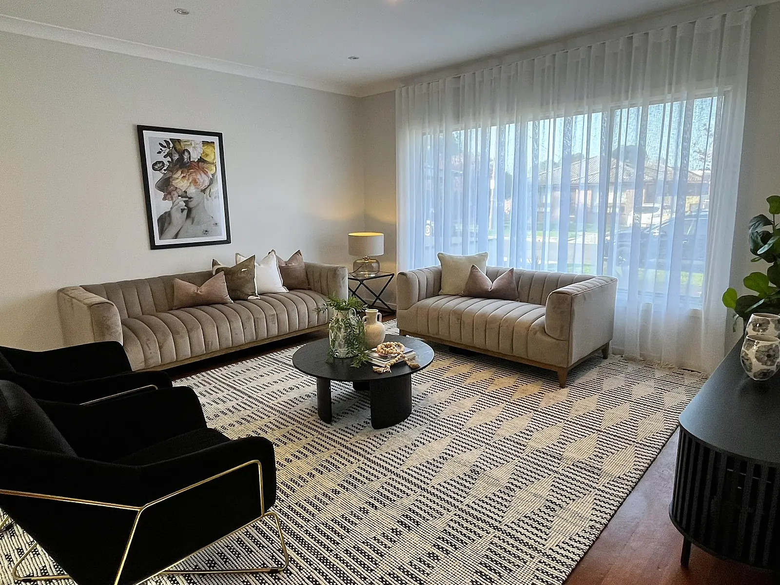 Lounge staged with velvet sofas and patterned rug on timber floors in a Sunshine home