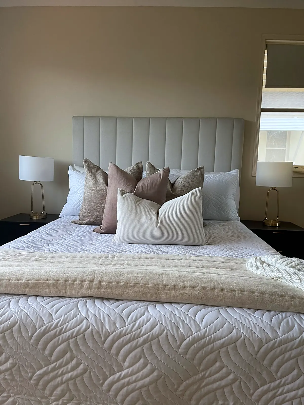 Main bedroom staged with cream bedhead and neutral linen in a Sydenham unit