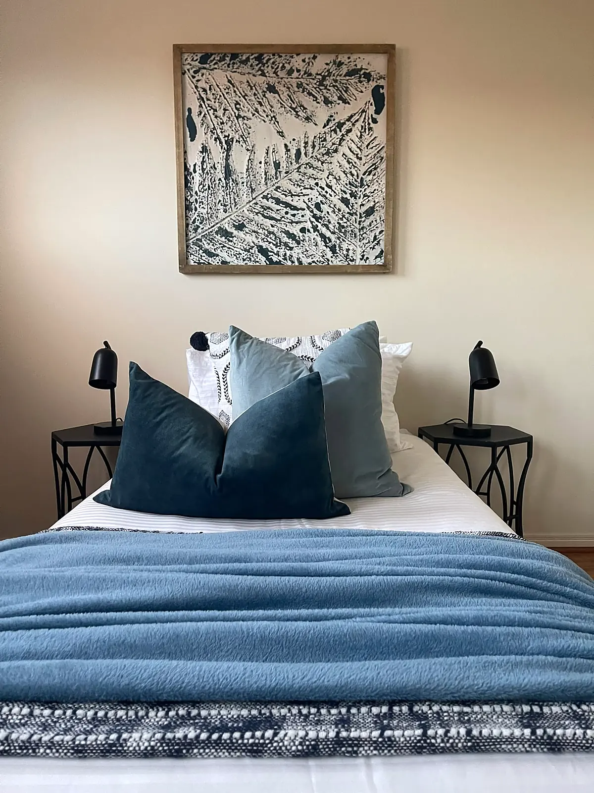 Bedroom styled with navy cushions and blue throw in a Sydenham unit