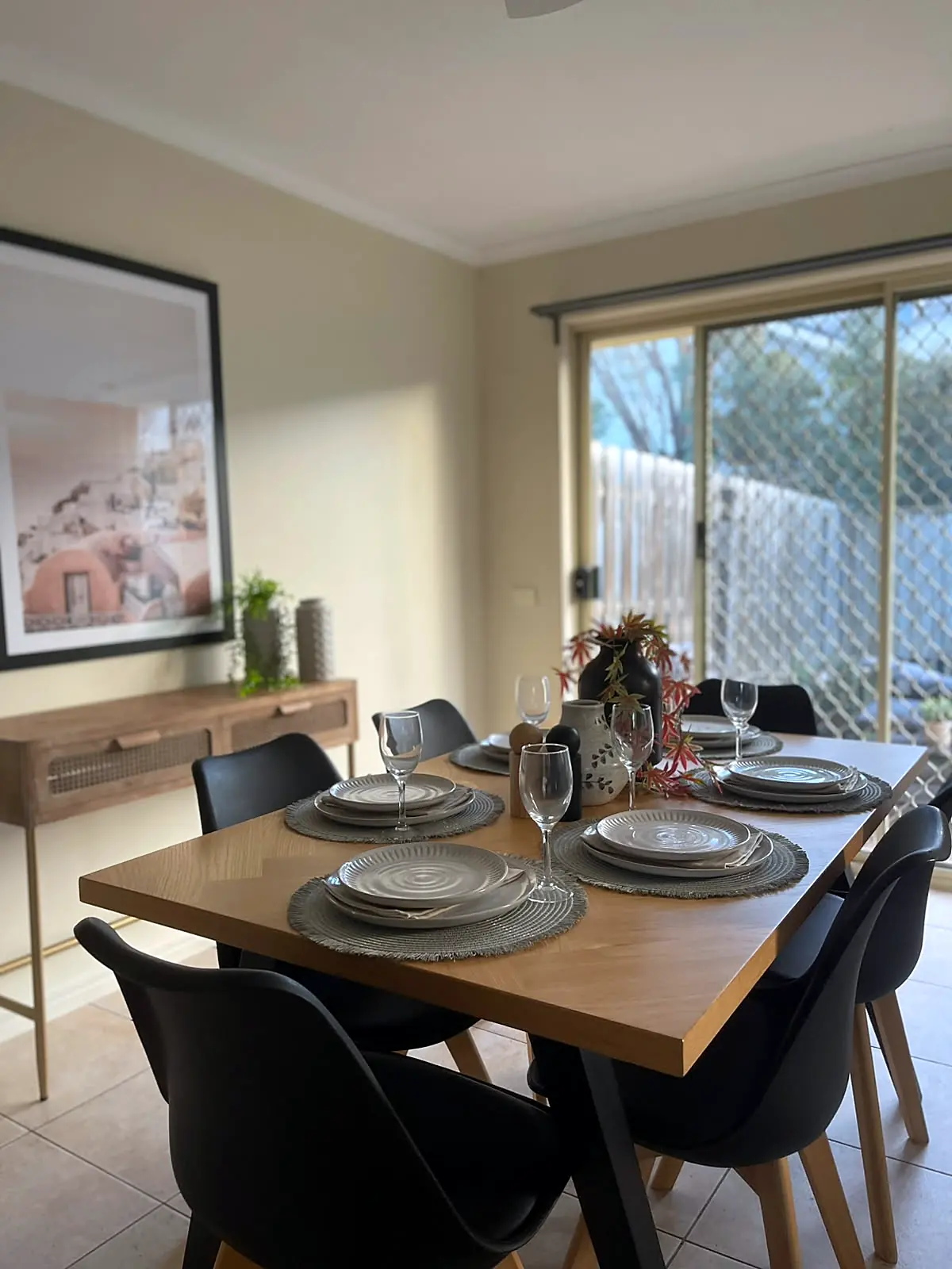 Timber dining table with black chairs beside the courtyard door in a staged Sydenham unit