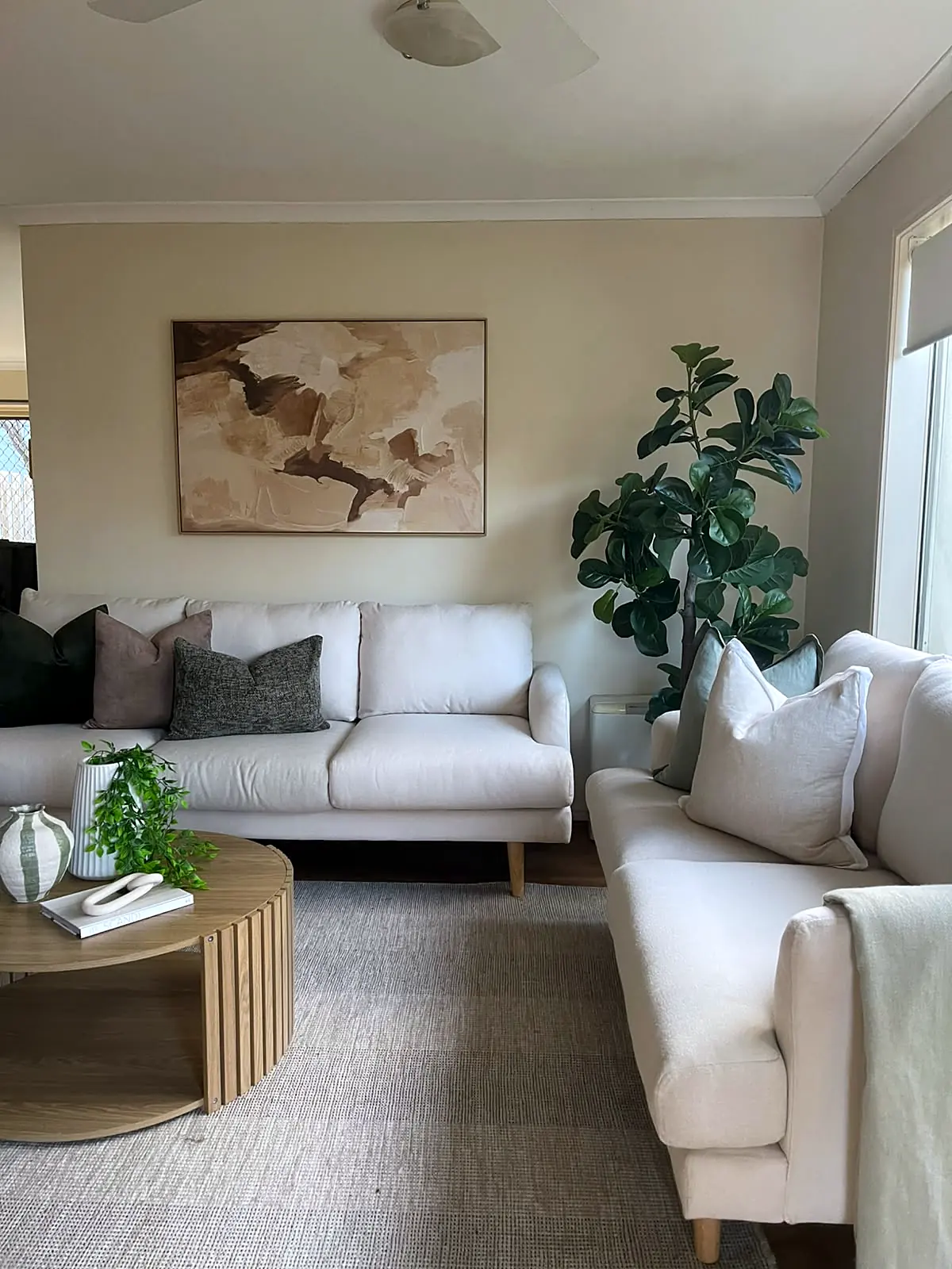 Living room with two cream sofas and ribbed timber coffee table in a staged Sydenham unit