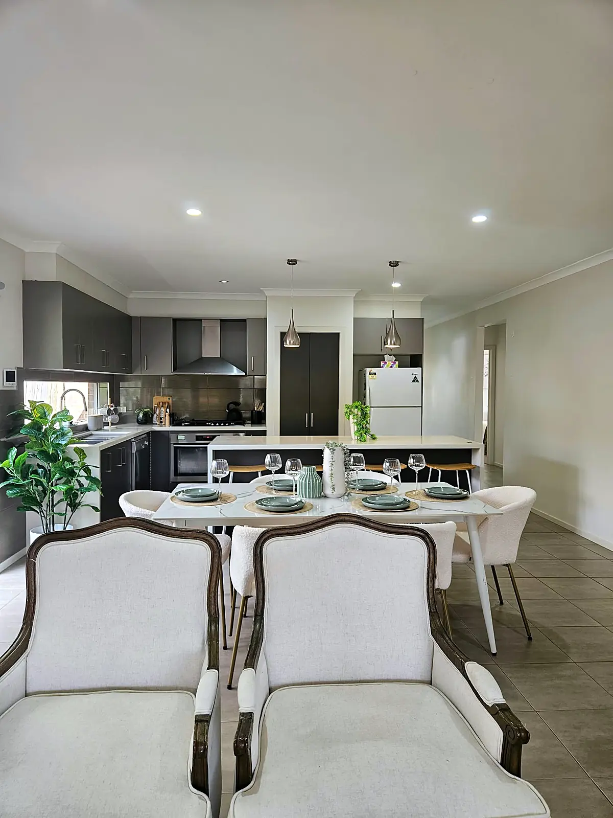 White dining table with upholstered chairs in front of the kitchen in a staged Taylors Hill home