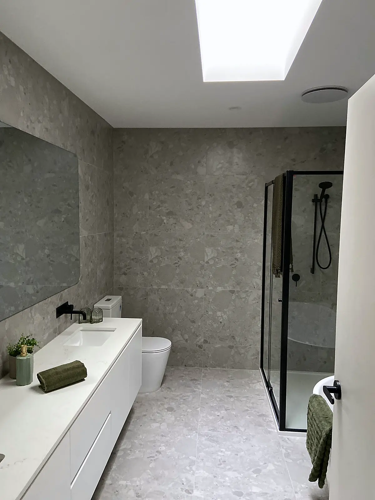 Stone-tiled bathroom styled with towels and greenery in a Thomastown townhouse
