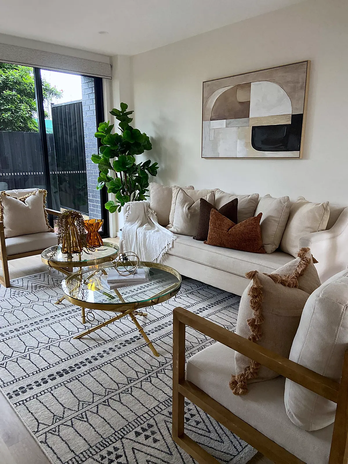 Lounge with timber-framed armchairs opening to the courtyard in a staged Thomastown townhouse