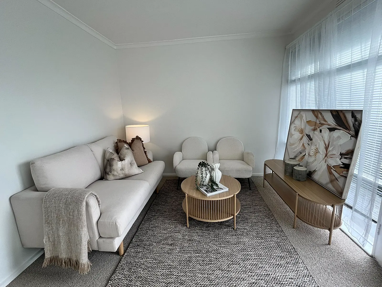 Living room staged with cream sofa and round timber coffee table in a Thornbury unit