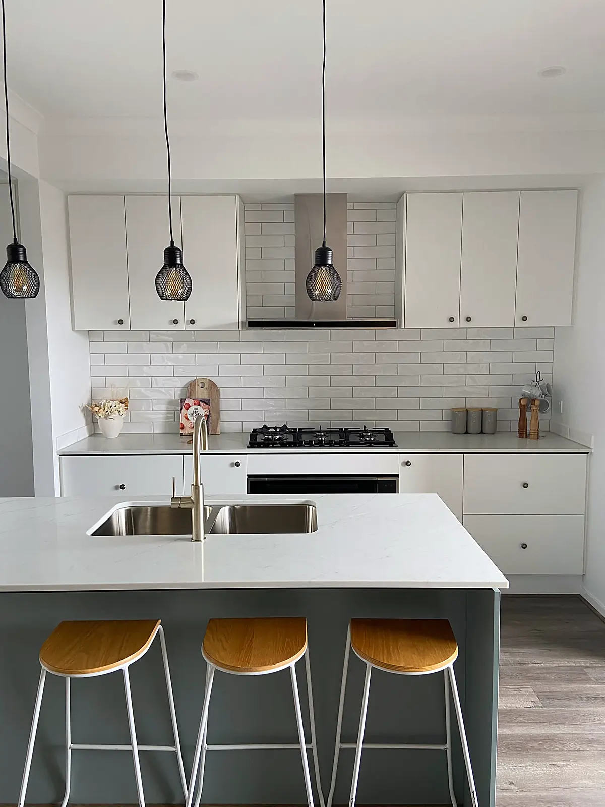 White kitchen with island bench and timber stools in a staged Truganina home