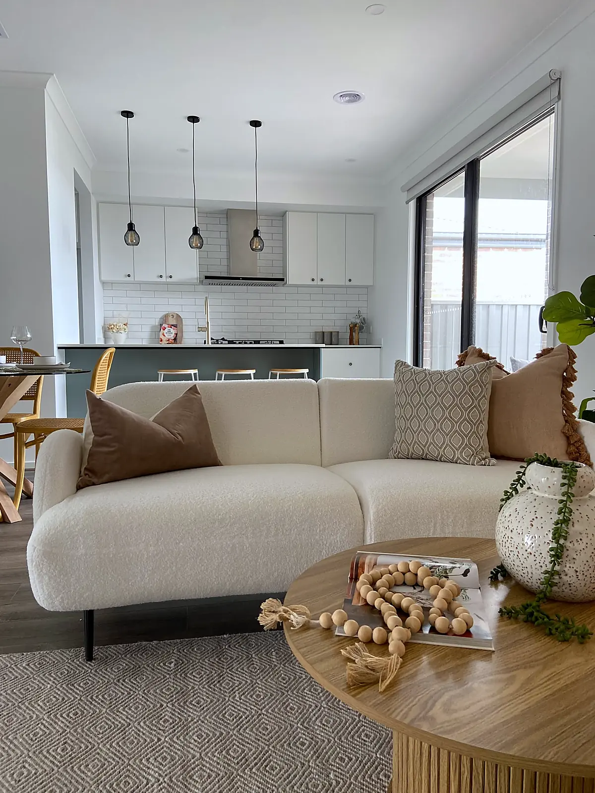 Open-plan living with boucle sofa beside a white kitchen in Truganina