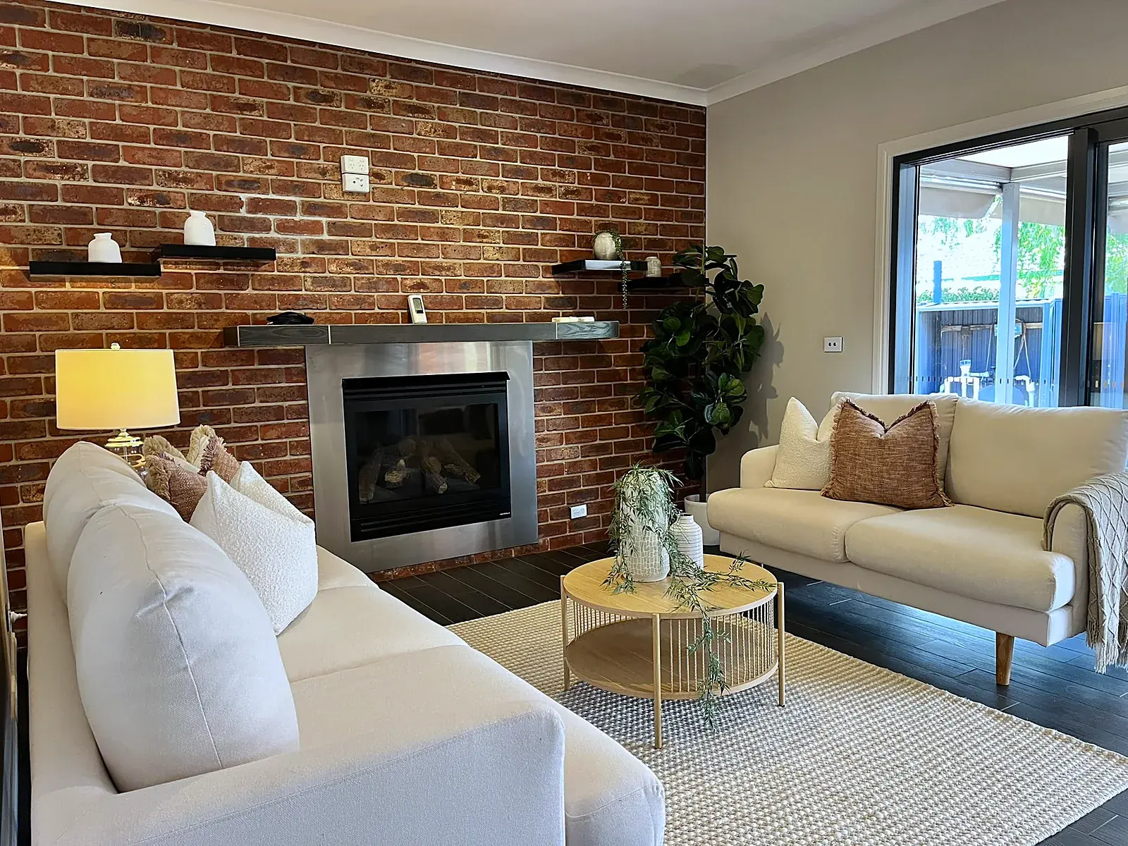 Lounge with brick feature wall styled with cream sofas in a Werribee home