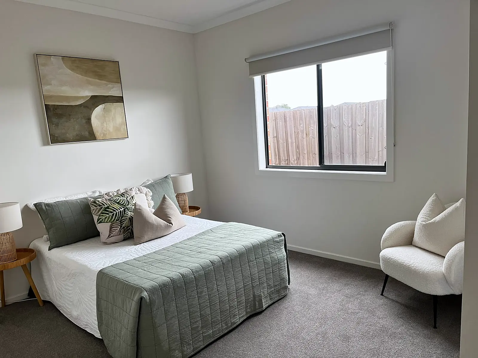 Bedroom staged with sage green quilt and armchair in a Wollert home