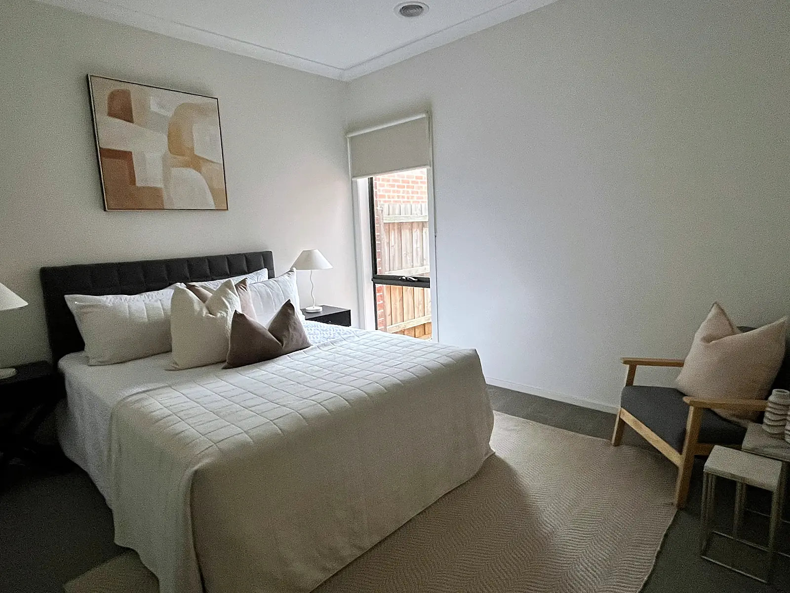 Main bedroom staged with dark bedhead and neutral linen in a Wollert home