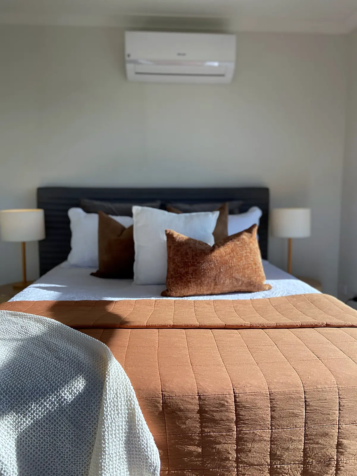 Main bedroom staged with dark bedhead and rust quilt in a Wyndham Vale home