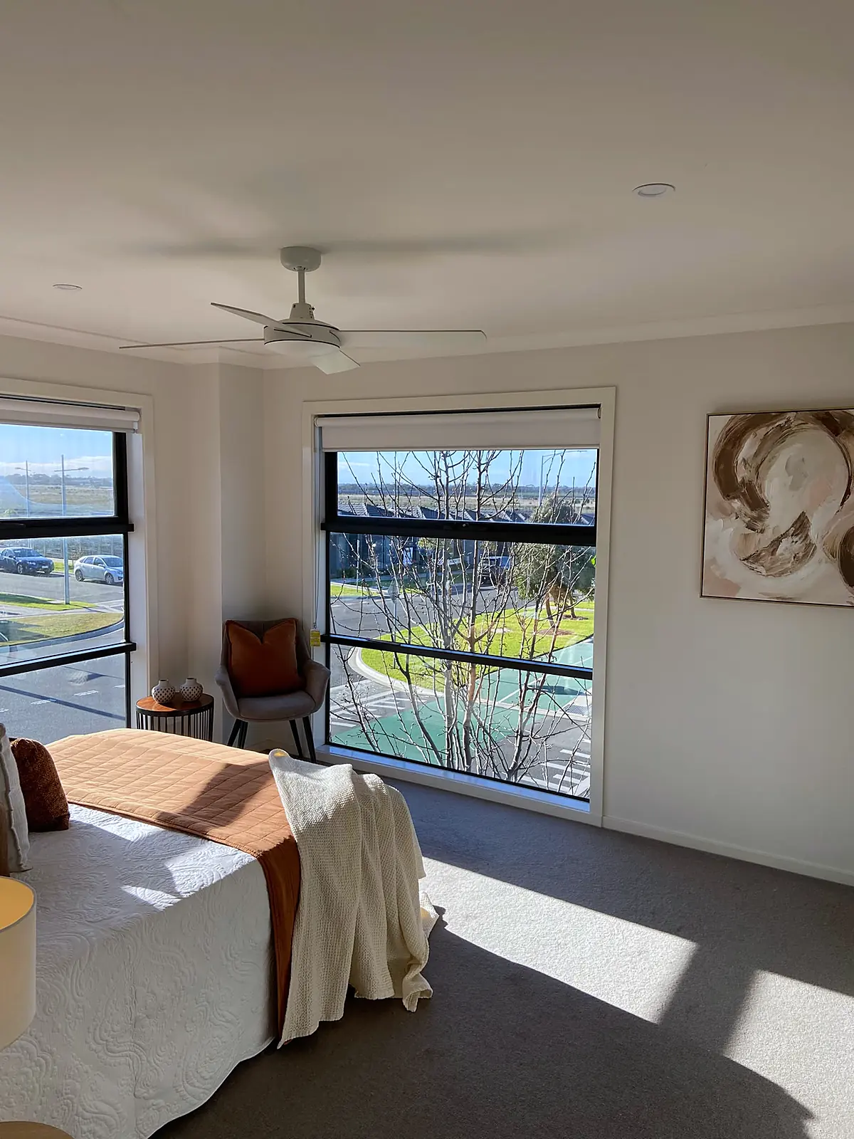 Sunny bedroom with wide windows styled in rust and cream in a Wyndham Vale home