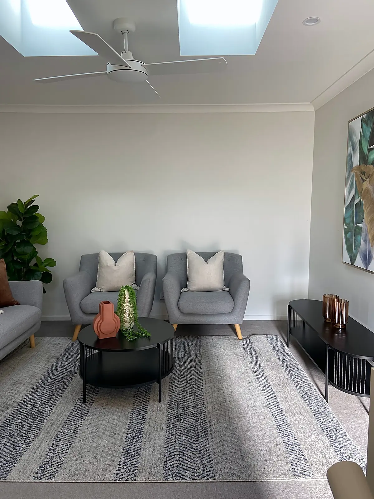 Second living area with two grey armchairs under a skylight in a staged Wyndham Vale home