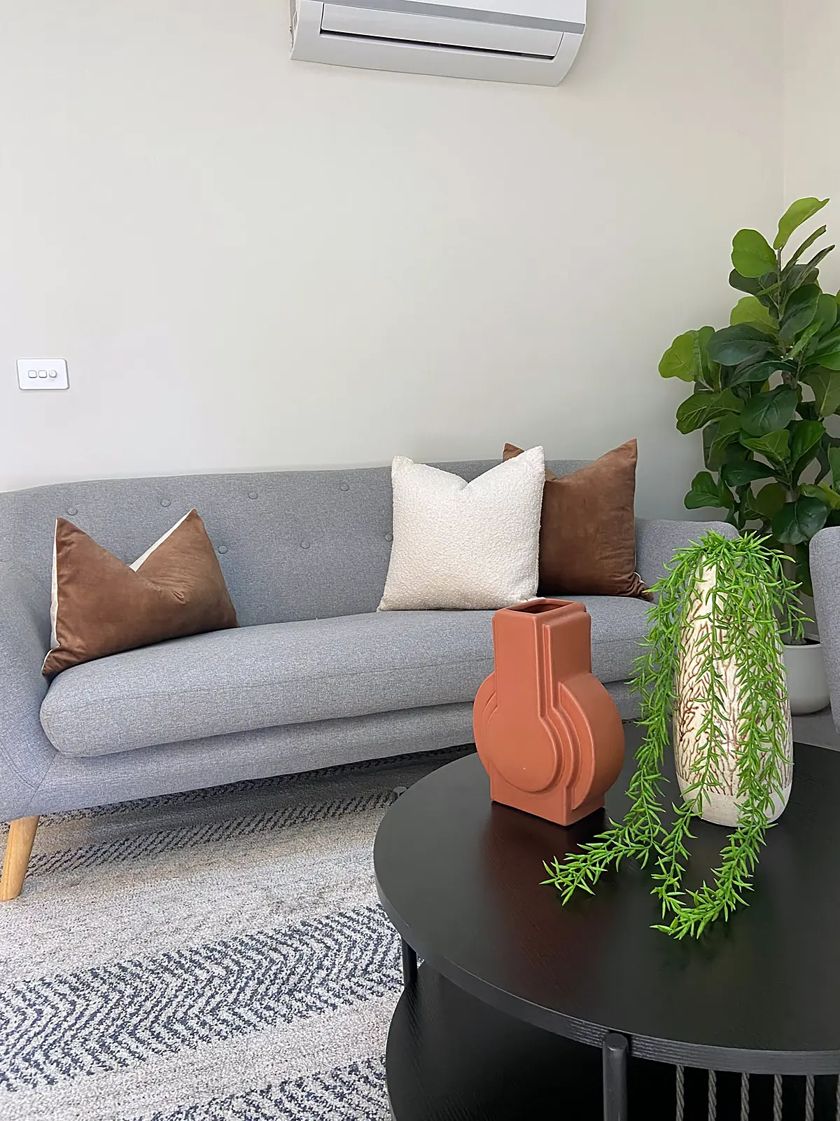 Grey sofa with cream and rust cushions and styled coffee table in a Wyndham Vale home